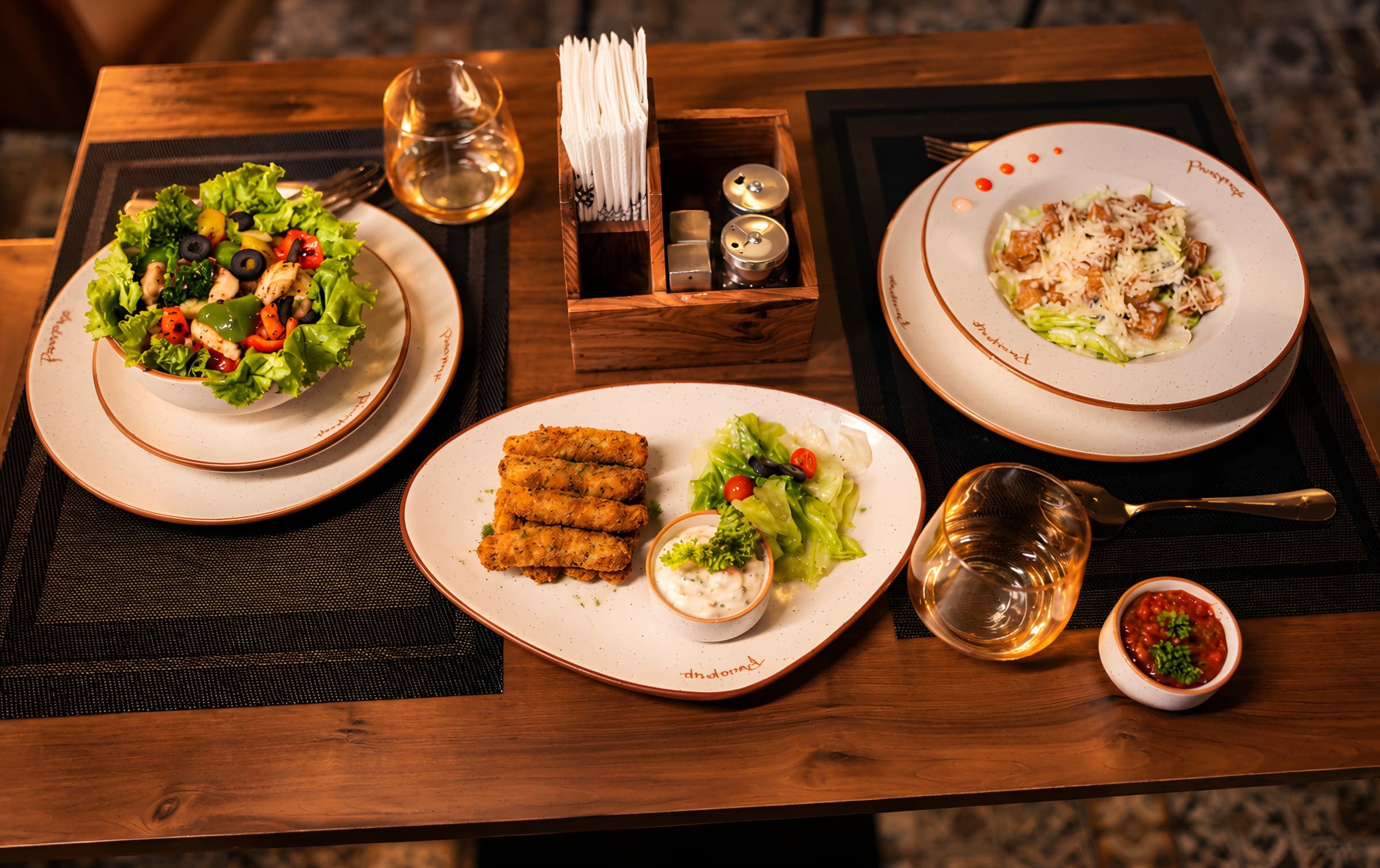 A spread of salads, crispy rolls and dips on a wooden table