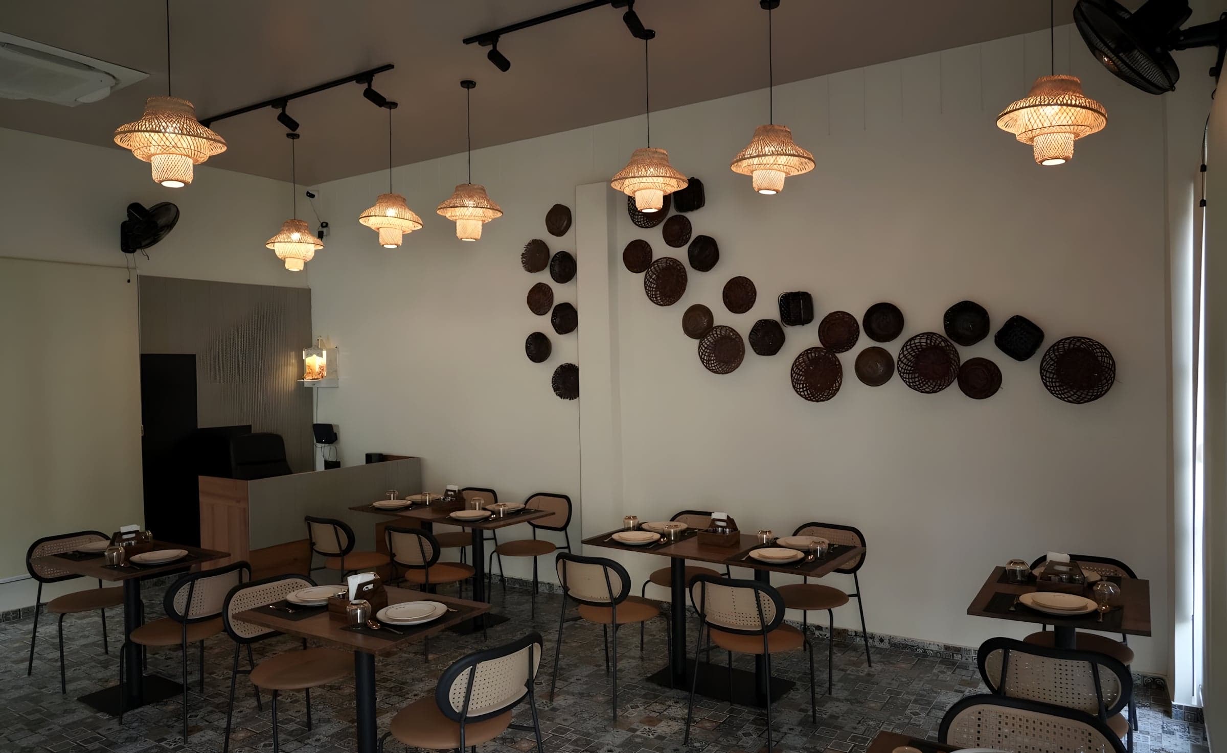 Rows of set tables under hanging woven lamps